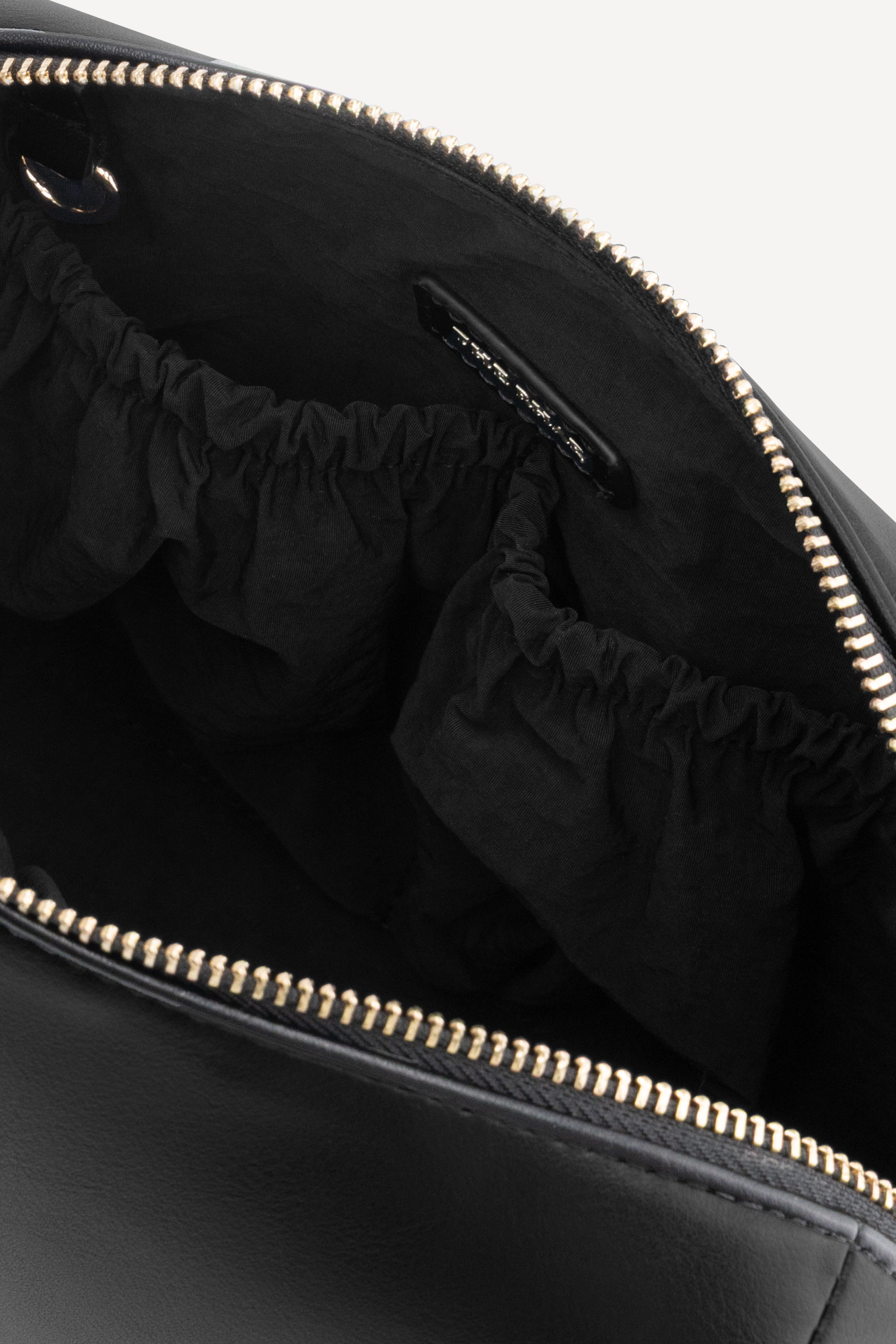 Interieur van The Lucy Black met elastische opbergvakken en goudkleurige ritssluiting